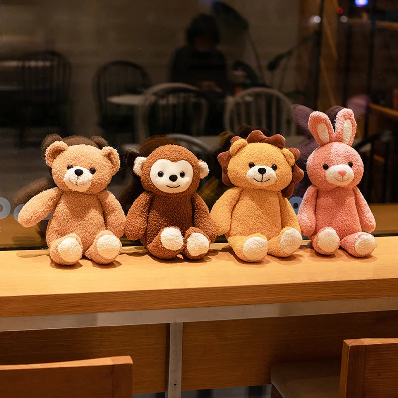 A collection of soft plush toys including a teddy bear, a monkey, a bear, and a rabbit, displayed side by side on a wooden surface.