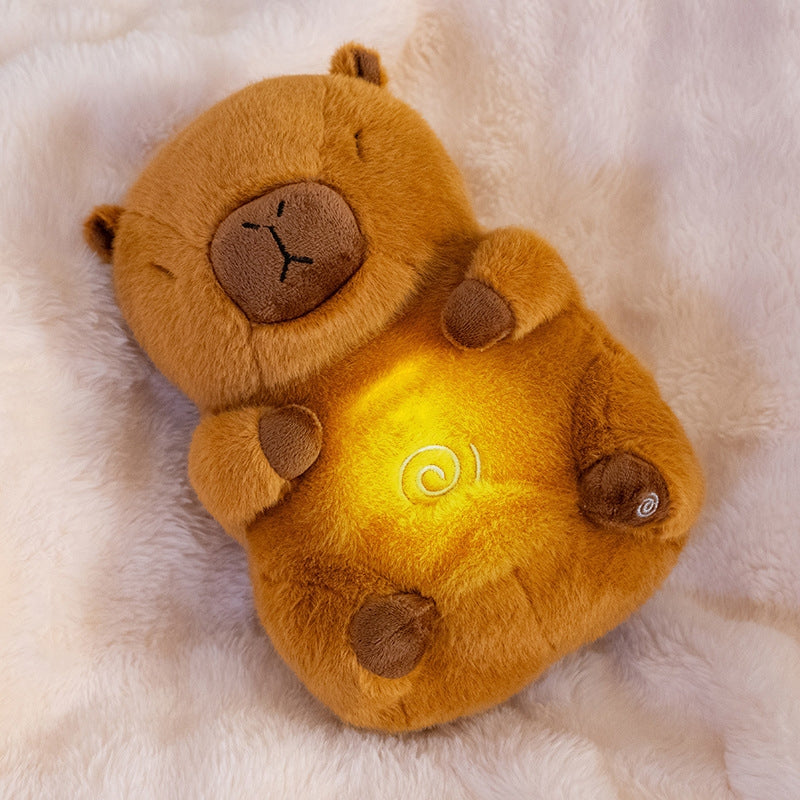 capybara plush toy lying on fluffy pink blanket, with a glowing belly