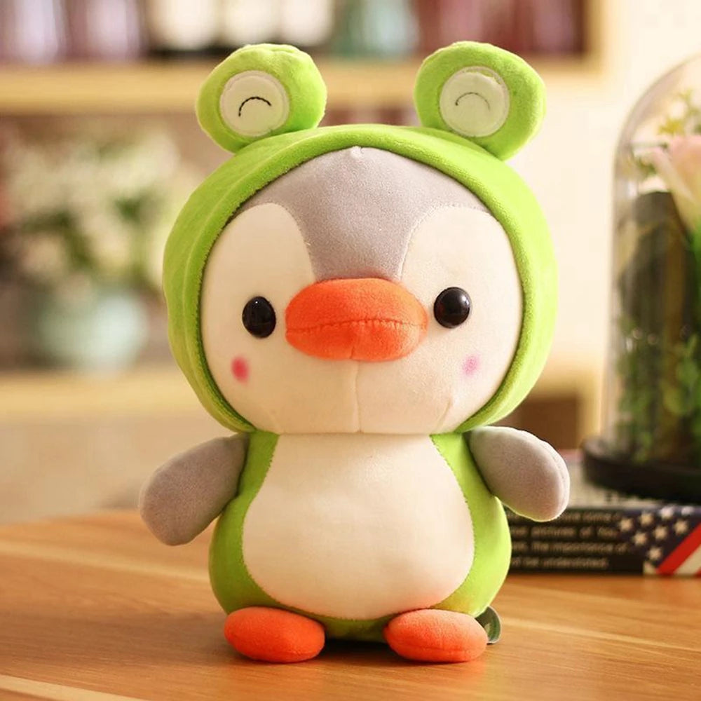 Plush toy penguin dressed in a green frog suit sitting on a wooden surface