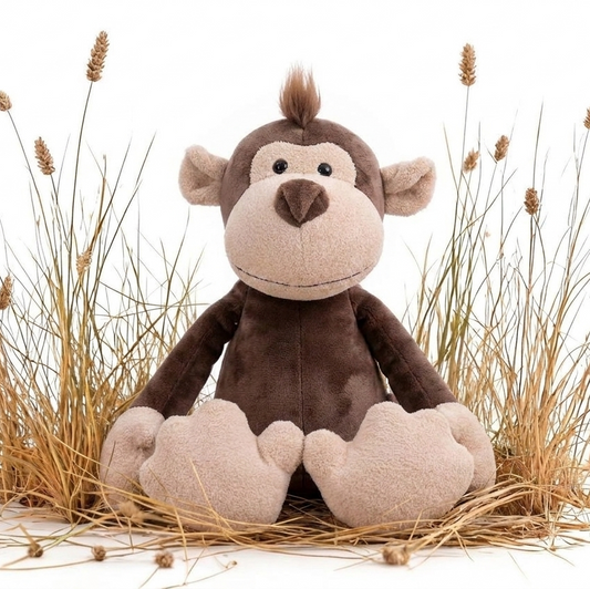 A plush stuffed monkey toy sitting upright among dried grass stems on a clean white background.