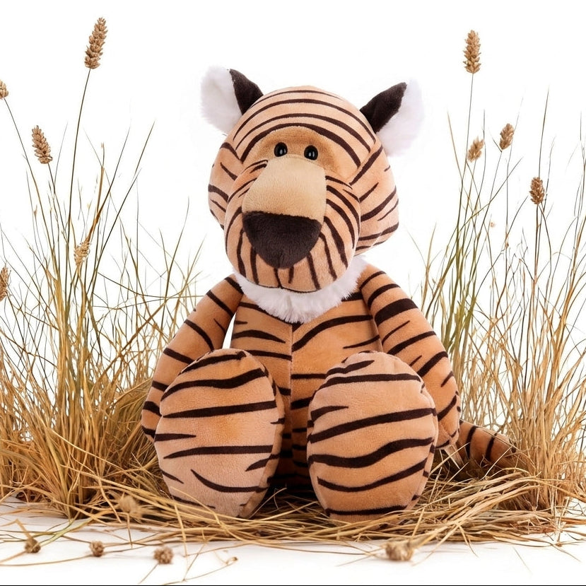 A plush tiger toy sitting upright among dried grass stems on a white background.